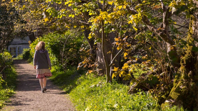 A visitor walks away down a path in the gardens at Godolphin Cornwall